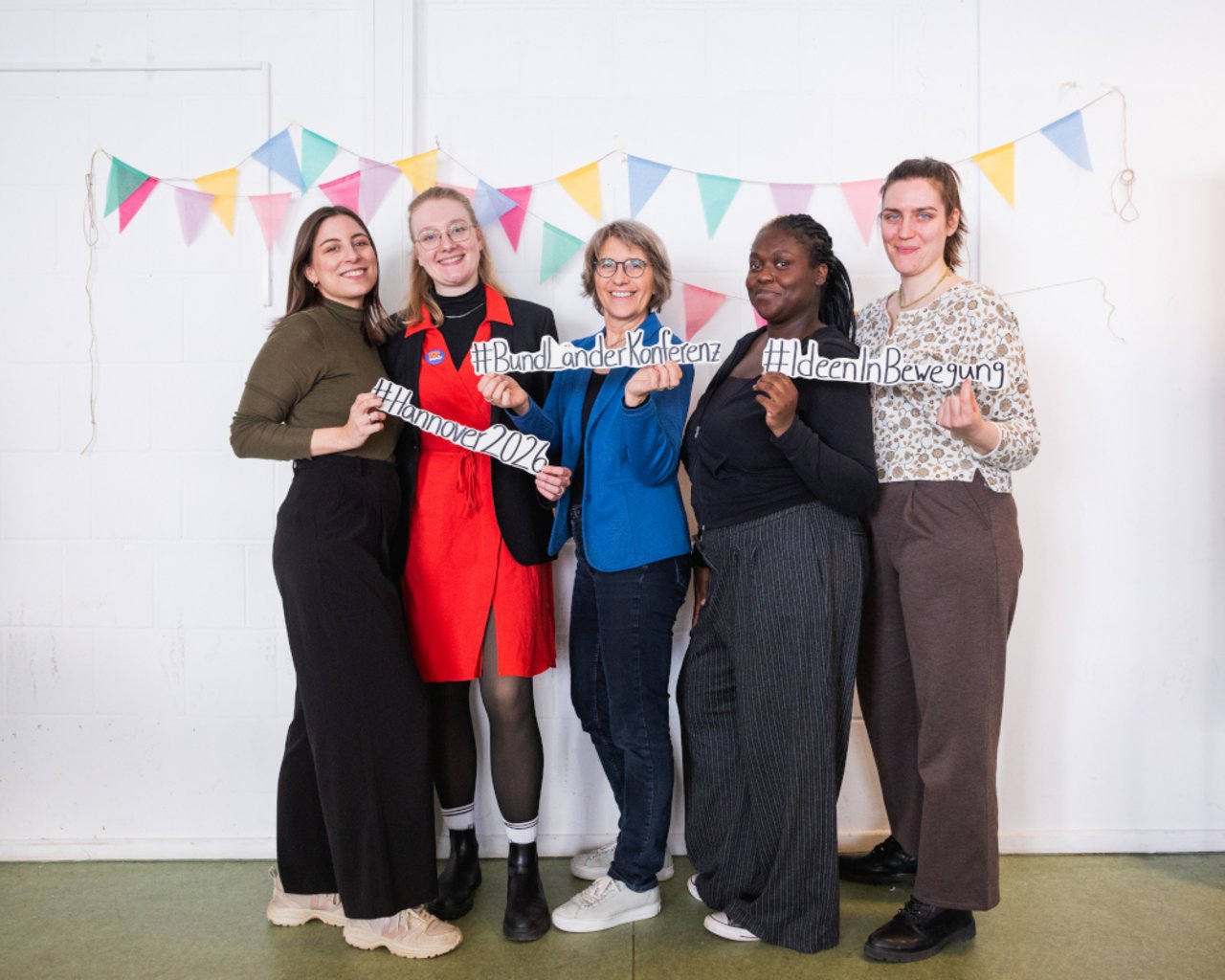 Auf diesem Bild ist das LKJ-Team mit den ausgedruckten Slogans #Hannover2026, #BundLänderKonferenz und #IdeenInBewegung zu sehen: Lea di Lena, Nele Altenburg, Anja Krüger, Carla Luwawa-Nkandu und Mareike Weihmann