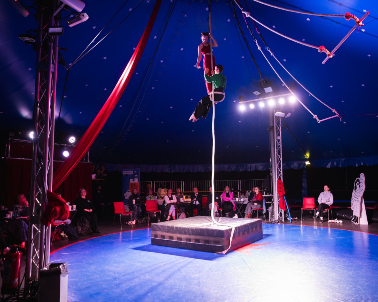 Das Bild zeigt einen weiten Blick auf die erleuchtete Manege, wo zwei Jugendliche ihr artistisches K&ouml;nnen am Seil zeigen.